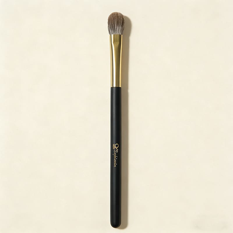Sophienia eyeshadow blending brush with soft gray bristles, gold ferrule, and black handle on cream background