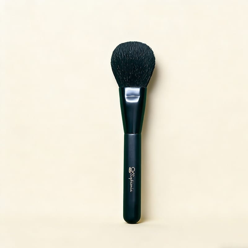 Black Sophienia makeup powder brush with soft rounded bristles and matte handle on cream background