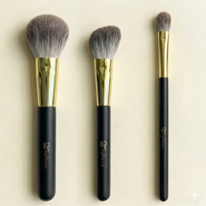 Three Sophienia makeup brushes in graduated sizes with gray bristles, gold ferrules, and black handles on cream background